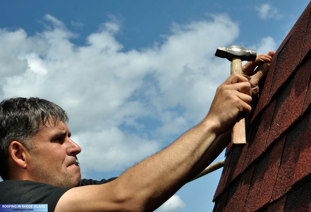A man with a nail in his mouth repairing the roof