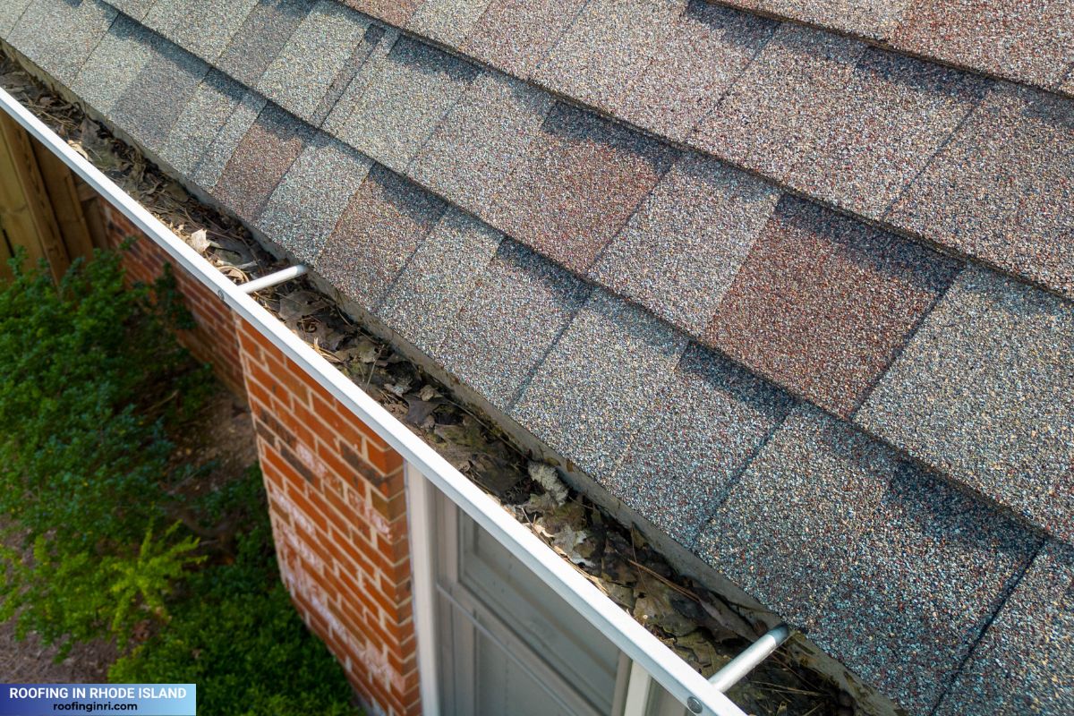 Metal gutters clogged with leaves and debris on a red brick residential house.