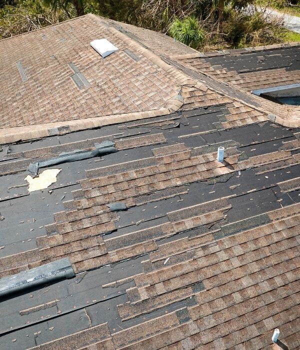 Damaged house roof with missing shingles after hurricane Ian in Florida. Consequences of natural disaster